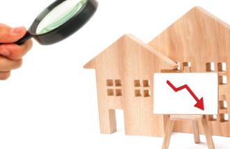 Wooden houses magnifying glass and lowered efficiency chart